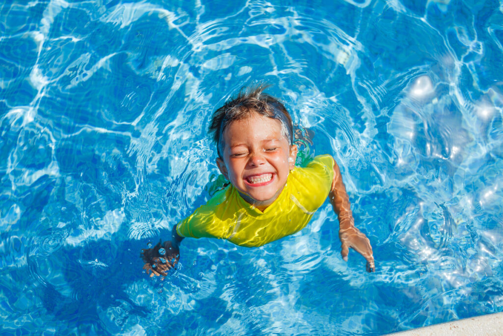 Cute happy little boy swimming in the pool.