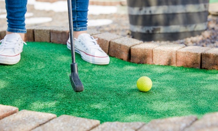 A woman putts a golf ball on he mini golf course.